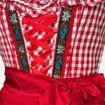 Red Bavarian rental dirndl by La Montana with lace-up bodice, floral trim, and red apron, available at Versatile OTM in Munich, owned by Beer&Pretzel Tours.