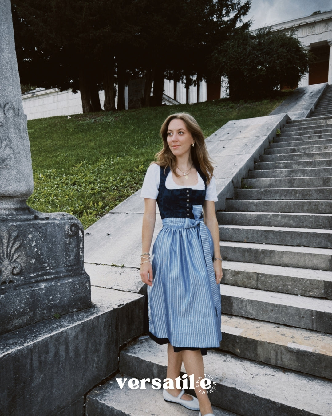 Apple of My Eye rental dirndl in Munich with deep blue jacquard floral bodice, silver buttons, and light blue pinstripe skirt—ideal for Oktoberfest dress hire.
