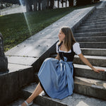 Versatile OTM Munich rental: Apple of My Eye dirndl featuring elegant floral jacquard bodice, silver clasp detail, and matching light blue skirt and apron.