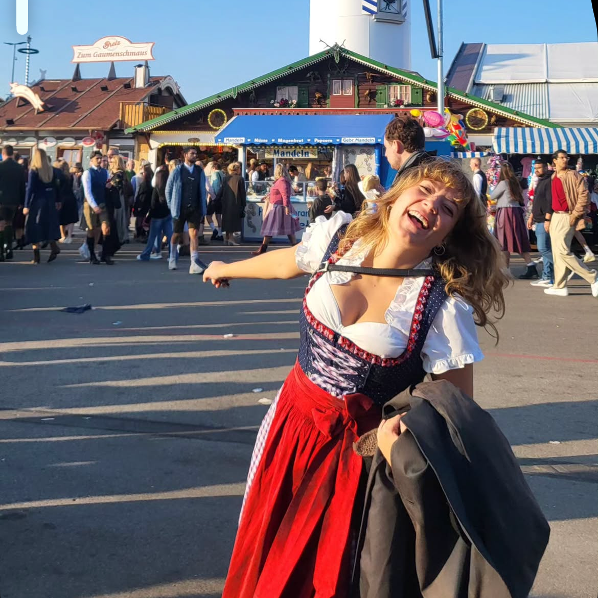 Boss Traditional Dirndl UGC, girl wearing a rented Dirndl from Versatile OTM for Oktoberfest laughing in front of a beer tent 