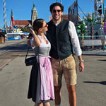 A woman in a traditional German dirndl with a lavender skirt and gray apron. Ready to rent a dirndl on Versatile OTM 