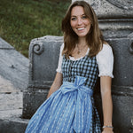Rent a Berwin & Wolff Bavarian dirndl with ornate silver buttons and romantic light blue apron, available in Munich for Oktoberfest.