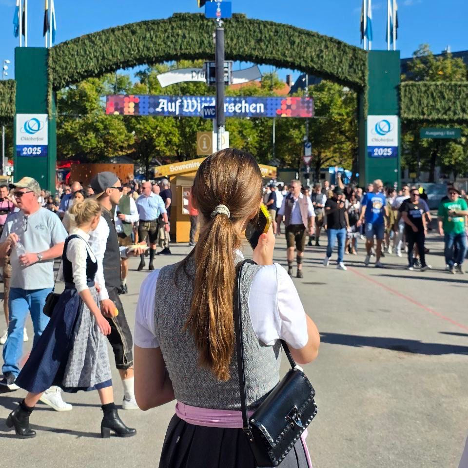 A woman in a traditional German dirndl with a lavender skirt and gray apron. Ready to rent a dirndl on Versatile OTM 