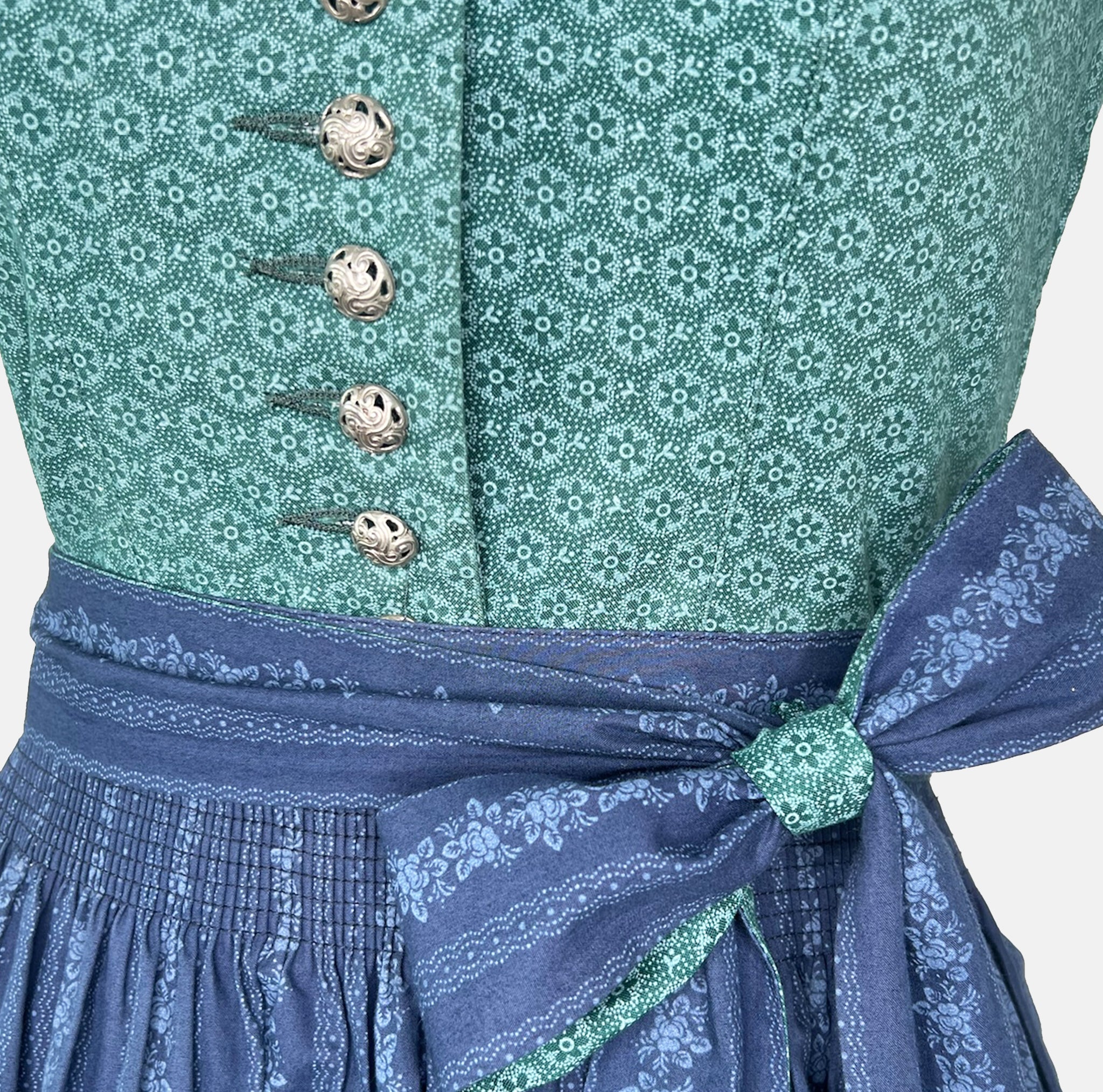 Dollar Tracht Dirndl with high-necked green bodice and deep blue patterned apron, available to rent at Versatile OTM.