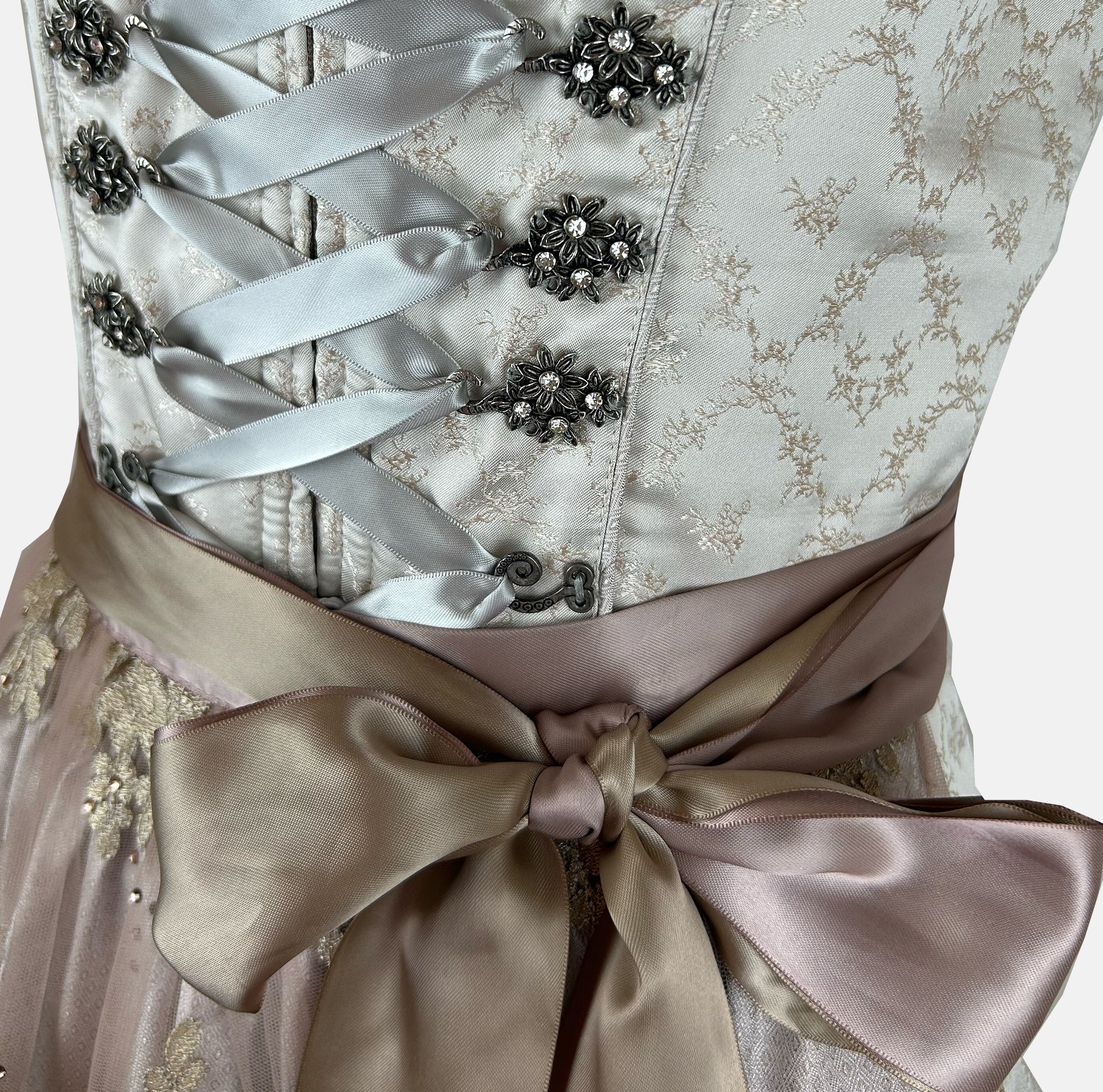 Close-up of a Krüger Dirndl featuring an ivory bodice with silver ribbon lacing and a gold embroidered apron. Skirt length 60cm. Elegant and luxurious.