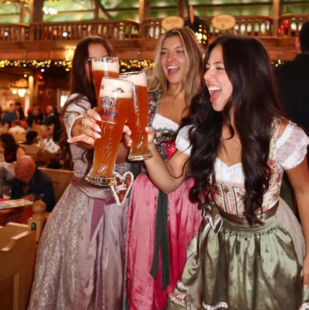 Three women in traditional cheeky Dirndl in a beer tent at Oktoberfest 
