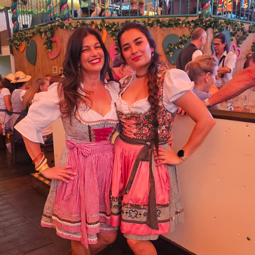 Two women posing in with traditional German Krueger Dirnld dresses at Oktoberfest. Dirndl ready to rent on Versatile OTM 