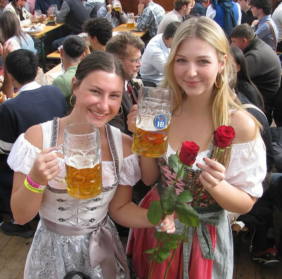 Two women posing in with traditional German Krueger Dirnld dresses at Oktoberfest. Dirndl ready to rent on Versatile OTM 