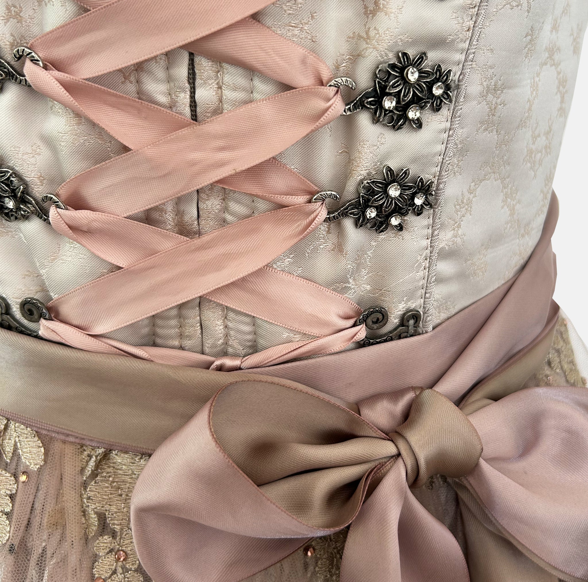 Krüger Bavarian rental dirndl with embroidered cream bodice, pink ribbon lacing, satin sash, and gold lace apron, available at Versatile OTM in Munich.