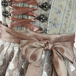 Krüger dirndl featuring an olive and taupe floral bodice, rose-gold ribbon lacing, and a mocha lace apron with white embroidered roses.