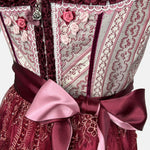 Burgundy Krüger dirndl with floral lace embroidery, satin ribbon bow, and decorative bodice – available for rent at Versatile OTM.