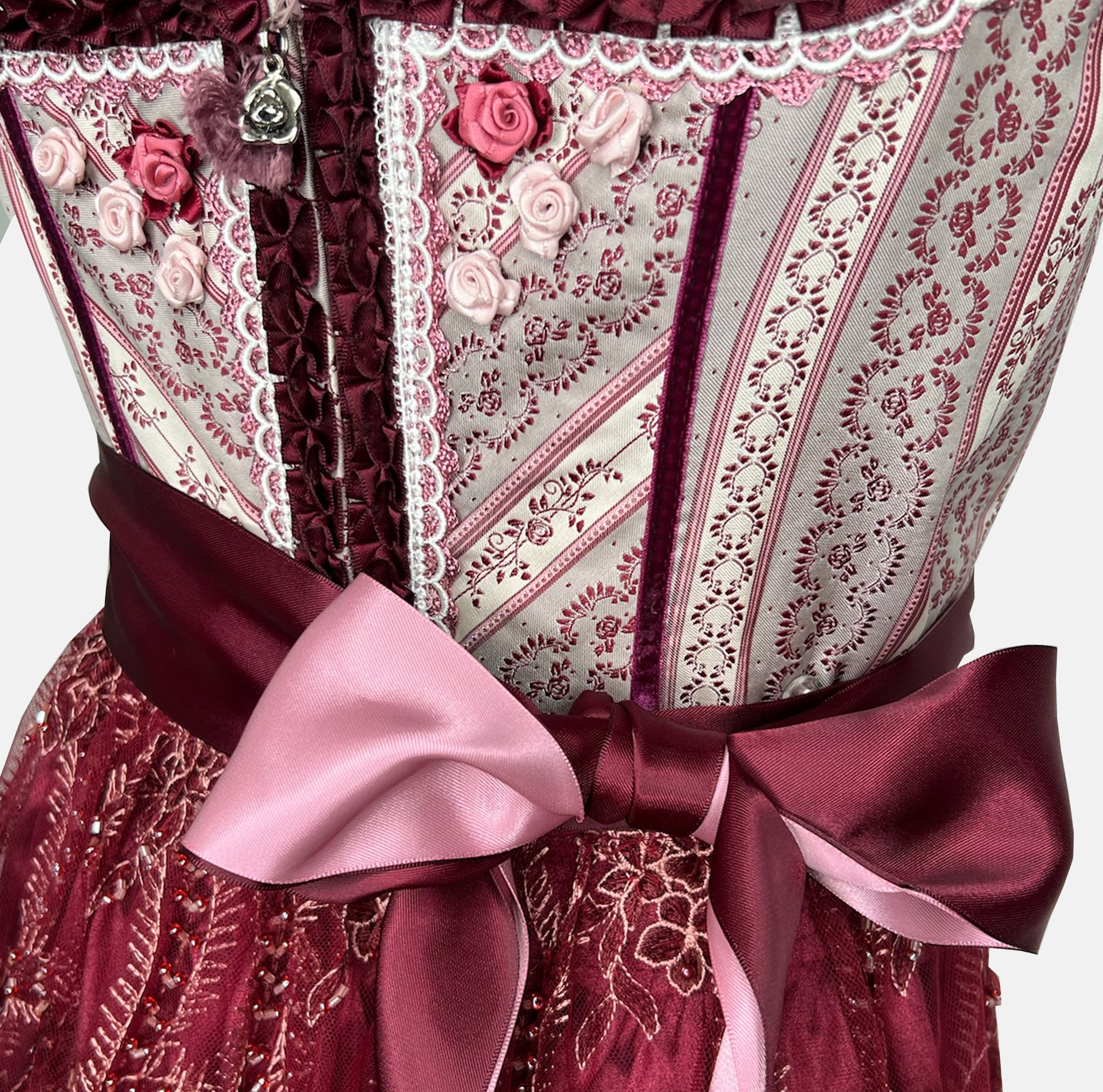 Burgundy Krüger dirndl with floral lace embroidery, satin ribbon bow, and decorative bodice – available for rent at Versatile OTM.