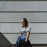 Rent Krüger mini dirndl in Munich: playful blue floral bodice with plunging neckline and matching apron, perfect for Oktoberfest.