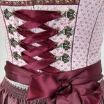Elegant Krüger dirndl with pink bodice, burgundy lacing, and satin apron. Classic 60 cm length – available to rent in Munich or online.