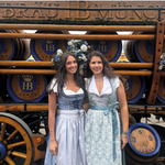 Girls wearing Dirndl infront of beer carriage. Dirndl rented on Versatile OTM for Oktoberfest wearing Krüger Dirndl Elegant Blue UGC