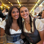 Girls wearing Krüger rented Dirndl from Versatile OTM for Oktoberfest, ready to rent. Sitting in an Oktoberfest tent in beautiful blue dirndl from Krüger