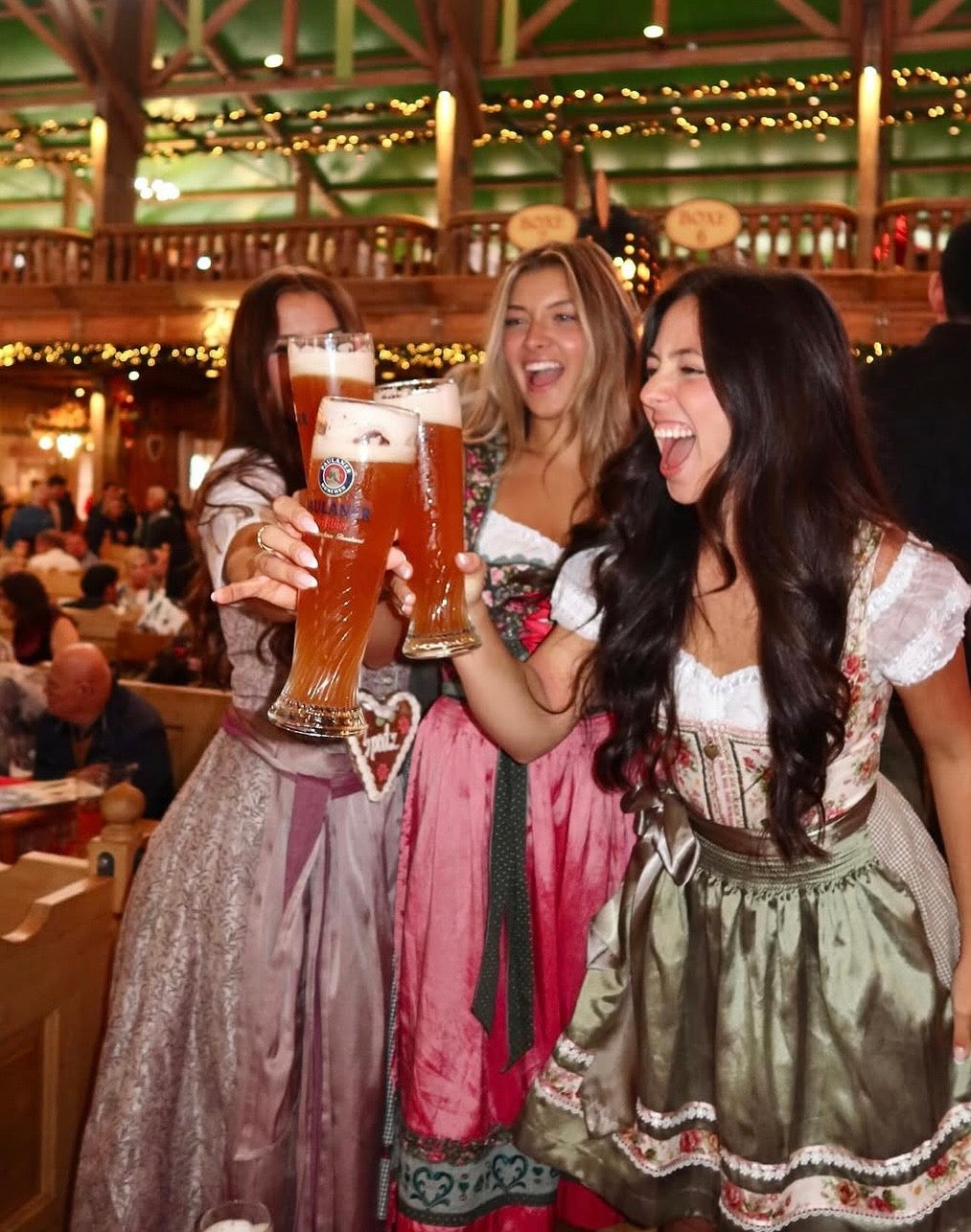 Three women in traditional cheeky Dirndl in a beer tent at Oktoberfest 