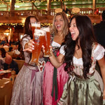 Three women in traditional cheeky Dirndl in a beer tent at Oktoberfest 