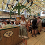 Woman in traditional Krüger Flower Dream Dirndl Bavarian in Oktoberfest Tent, holding a beer stein.