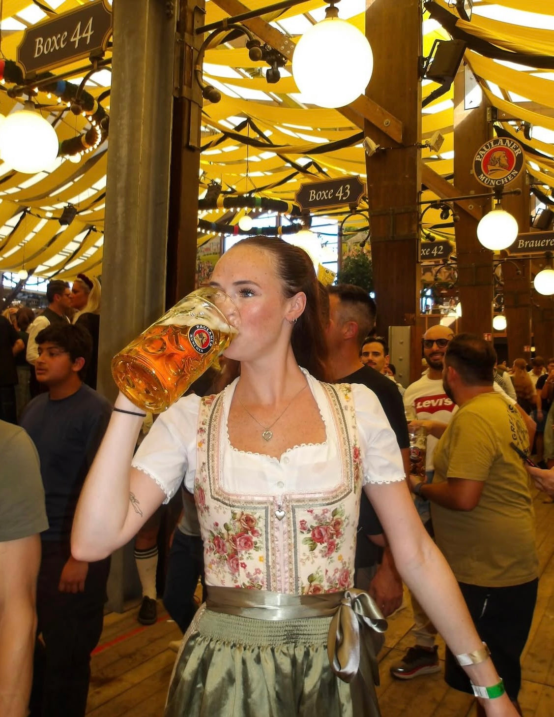Woman in traditional Bavarian Dirndl holding a large beer stein in a festive Oktoberfest tent