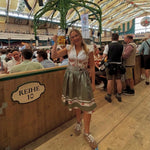 Woman in traditional Krüger Flower Dream Dirndl Bavarian in Oktoberfest Tent, holding a beer stein. Dirndl Dress ready to rent on Versatile OTM 