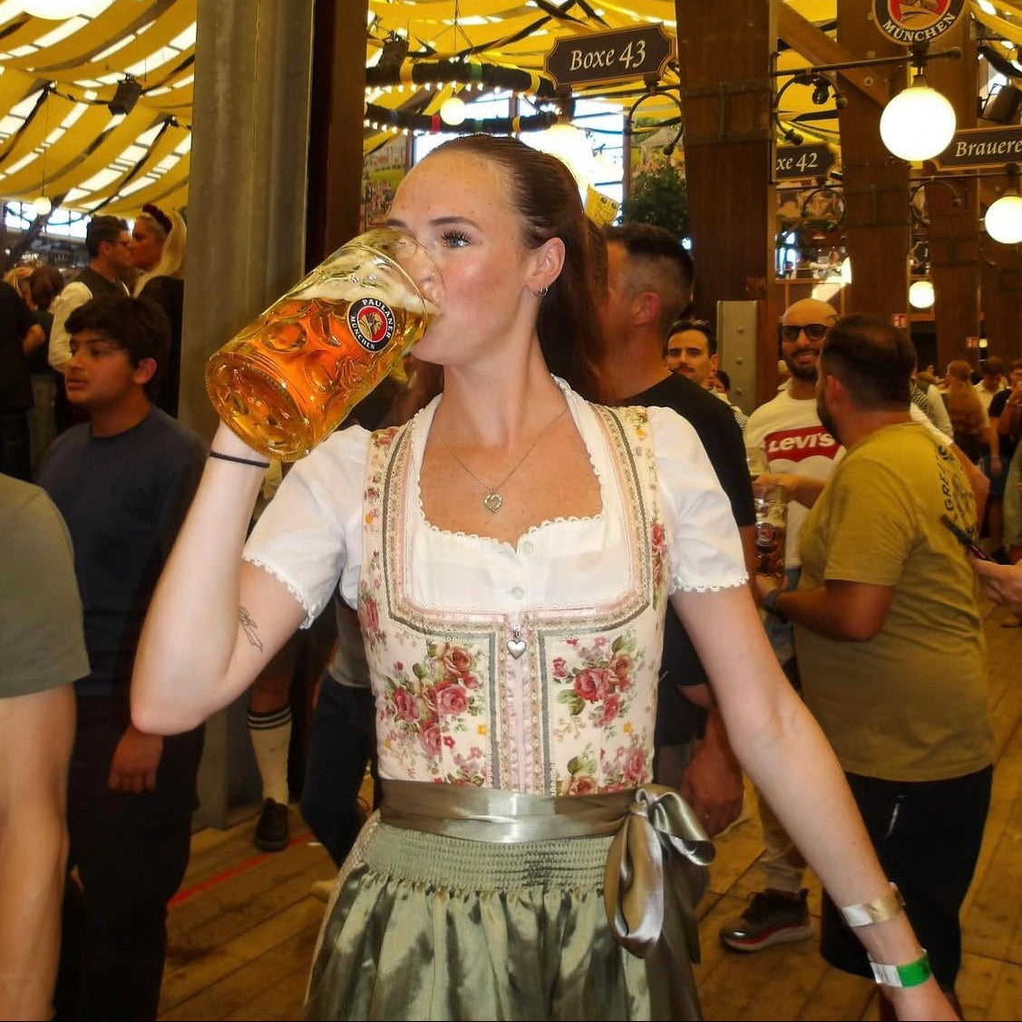 Woman in traditional Bavarian Dirndl holding a large beer stein in a festive Oktoberfest tent
