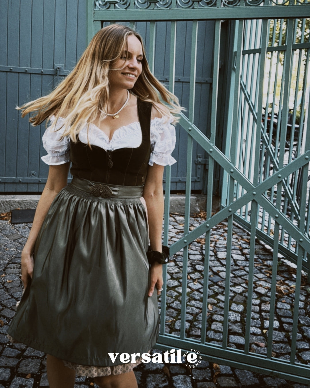 Elegant MarJo Bavarian dirndl rental in Munich: deep olive green velvet, gold-tone zipper details, flowing beige-accented skirt—Oktoberfest ready.”