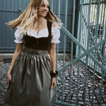 Elegant MarJo Bavarian dirndl rental in Munich: deep olive green velvet, gold-tone zipper details, flowing beige-accented skirt—Oktoberfest ready.”