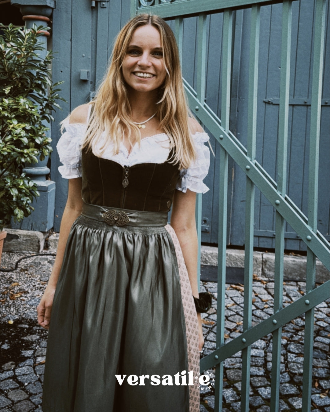 Rent a MarJo dirndl in Munich—olive velvet top, gold buckle, A-line skirt with beige pattern; perfect for Oktoberfest celebrations.