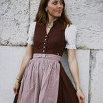 Elegant Marjo Bavarian dirndl rental with burgundy V-neck bodice, button-front detail, and flowing beige skirt — ideal for Oktoberfest in Munich.