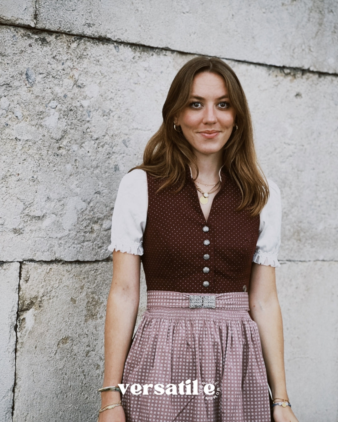Oktoberfest-ready Marjo dirndl for rent: burgundy jacquard V-neck bodice, silver-tone buttons, beige embossed skirt — available at Versatile OTM Munich.