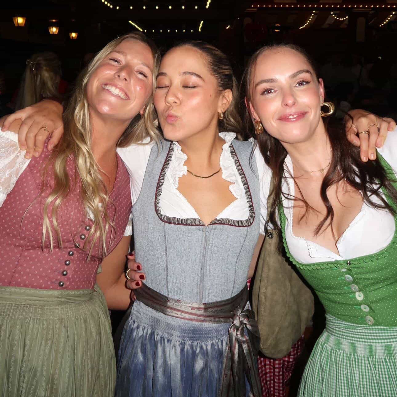 Three women wearing rented Dirndls from Versatile OTM for Oktoberfest. Classic Dirndl rentals in Blue, Red and Green Dirndls