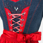 Cheeky red and navy dirndl with gingham bodice, lace-up detail, and red satin apron, available for rental at Versatile OTM, owned by Beer&Pretzel Tours
