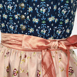 Trachtenmanufaktur Bavarian rental dirndl with navy floral bodice and rose embroidered apron, available at Versatile OTM in Munich, owned by Beer&Pretzel Tours.
