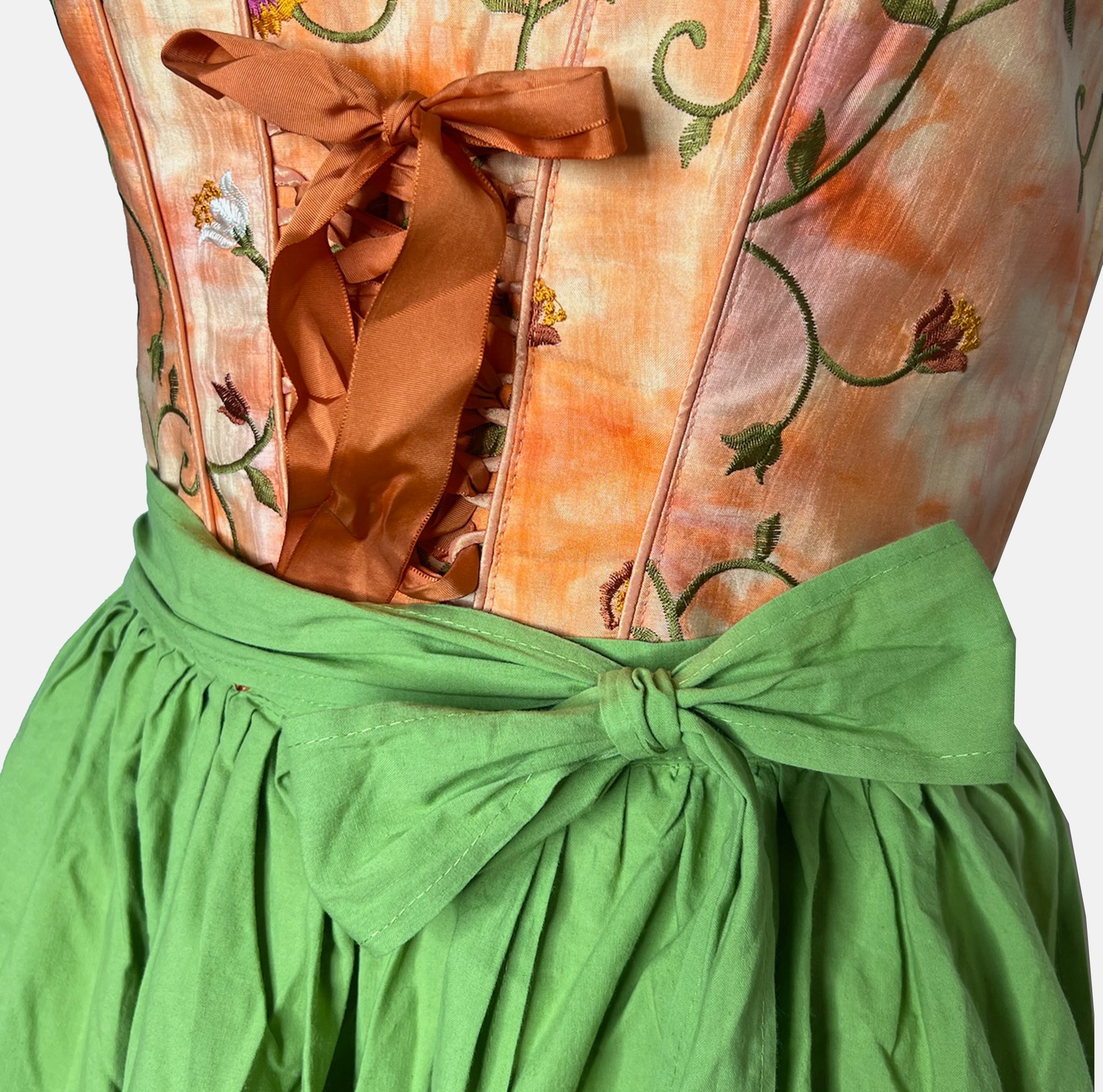 Tramontana Bavarian rental dirndl with orange embroidered satin bodice and green embroidered apron, available at Versatile OTM in Munich.