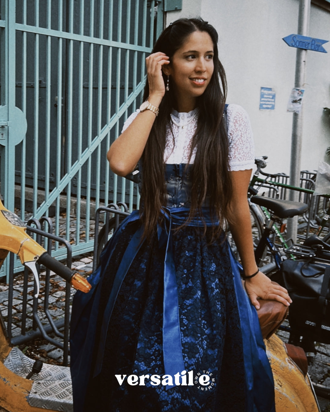 Woman wearing a blue lace dress Dirndl Pia form the versatile collection with 'versatile' branding in an urban setting ready for Oktoberfest