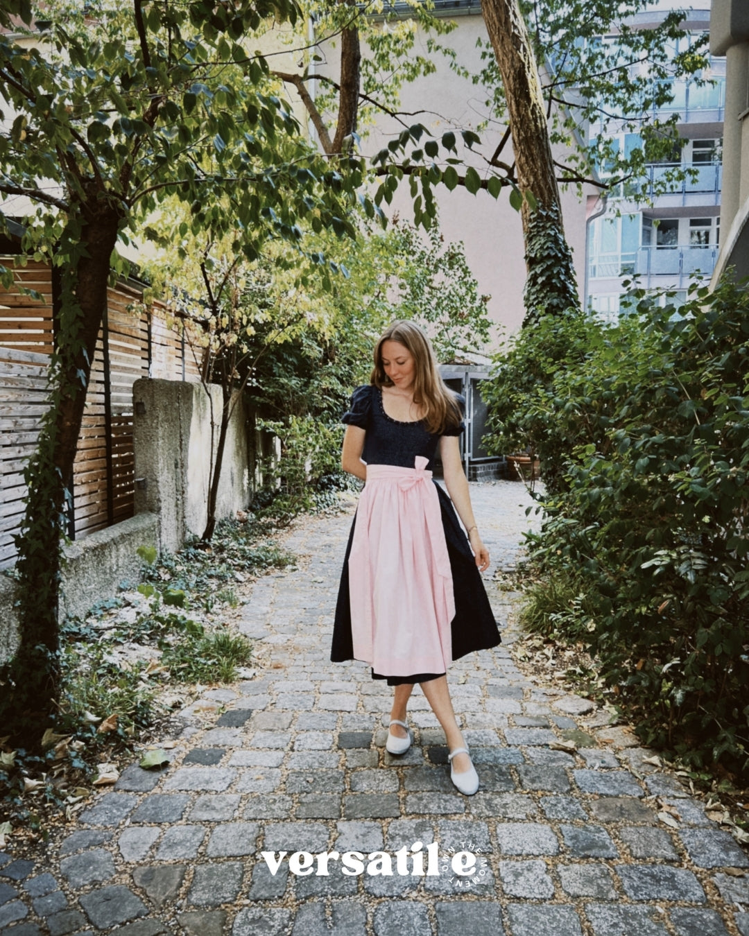 Premium Versatile Collection Dirndl Shannon rental: navy bodice, pink apron, elegant 70 cm skirt—for Oktoberfest in Munich.