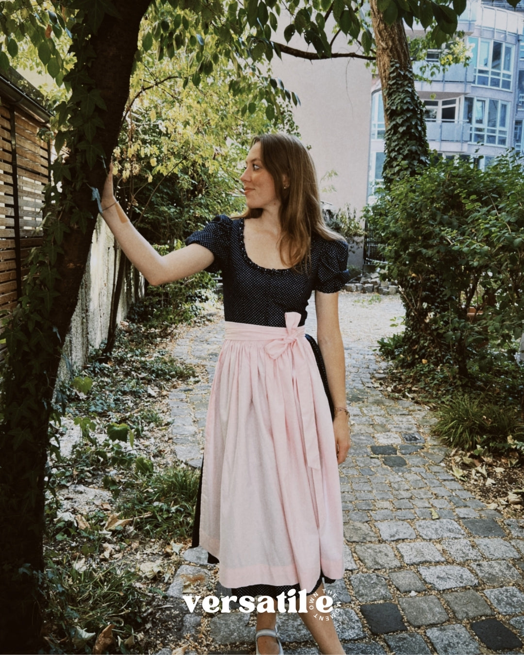 Premium Versatile Collection Dirndl Shannon rental: navy bodice, pink apron, elegant 70 cm skirt—for Oktoberfest in Munich.