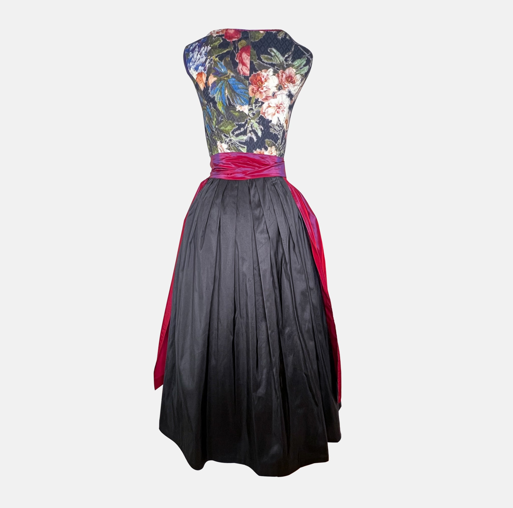 A traditional German Dirndl dress featuring a floral embroidered bodice and a deep red satin apron. 

Oktoberfest ready to rent our Versatile Collection Dirndl Celine