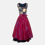 A traditional German Dirndl dress featuring a floral embroidered bodice and a deep red satin apron. 

Oktoberfest ready to rent our Versatile Collection Dirndl Celine