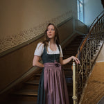 Handcrafted Dirndl Mia from Versatile Collection—romantic green floral design with plum apron, flattering silhouette, available for Oktoberfest dress hire in Munich.