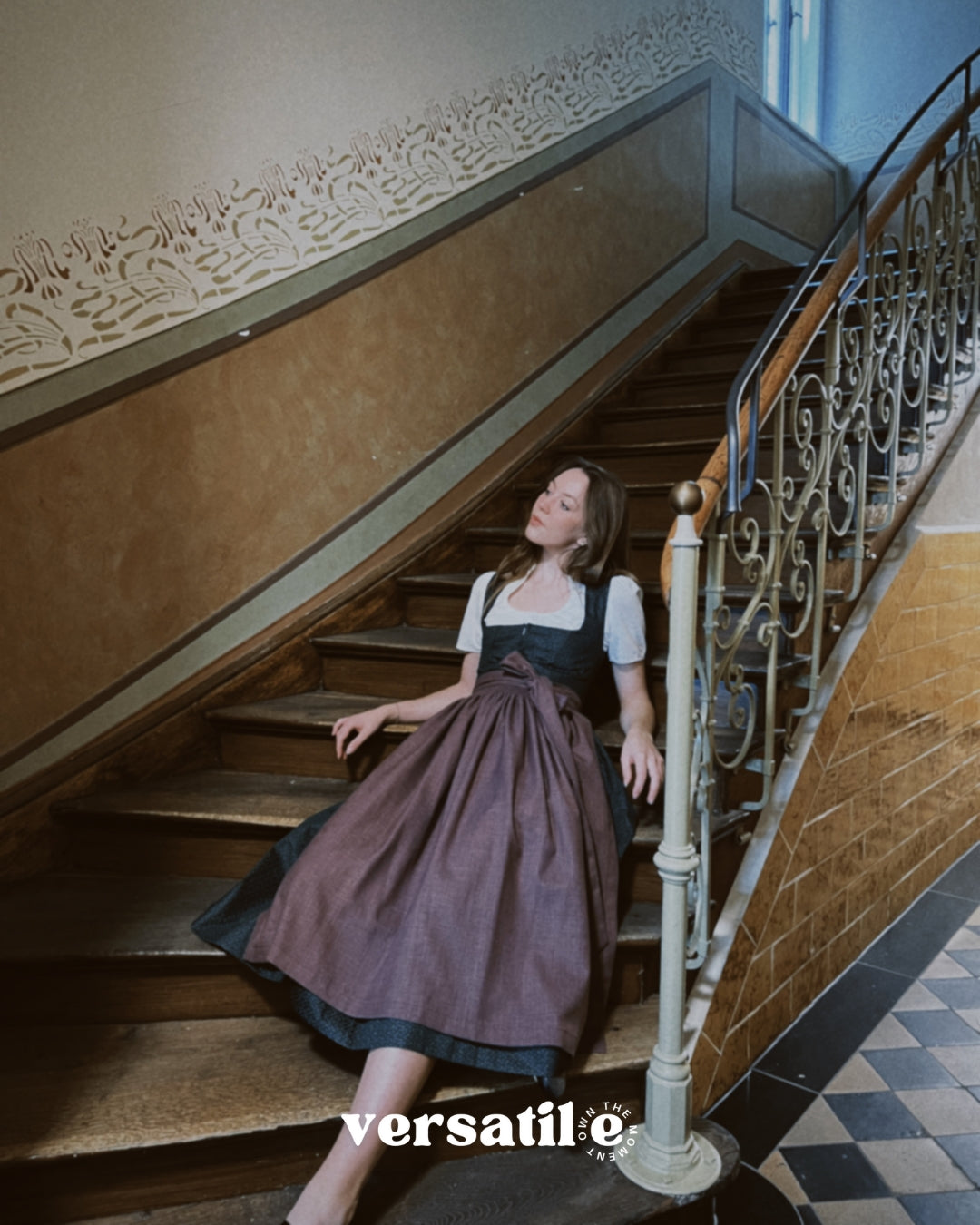 Versatile Collection Dirndl Mia in Munich—green floral printed bodice with plum linen apron and wide bow, handcrafted for Oktoberfest rental.