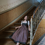 Versatile Collection Dirndl Mia in Munich—green floral printed bodice with plum linen apron and wide bow, handcrafted for Oktoberfest rental.
