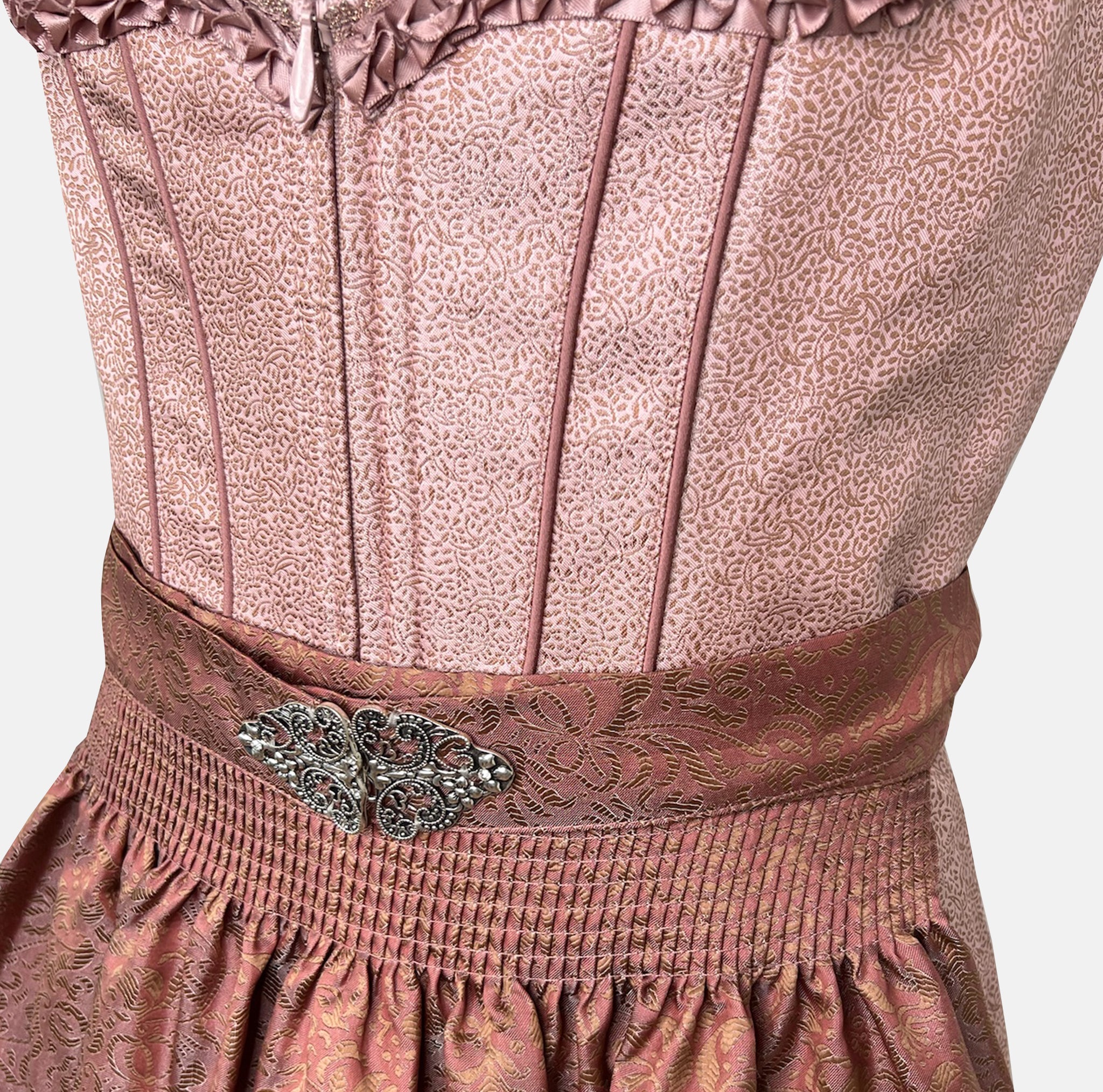 Detail: Short Krüger Dirndl Zafina with shimmering rose-pink bodice, heart-shaped neckline, and brown patterned apron – available to rent via Versatile.