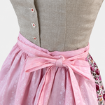 Detail of Almsach Dirndl with textured grey beige buttoned bodice and pink apron bow with white floral pattern