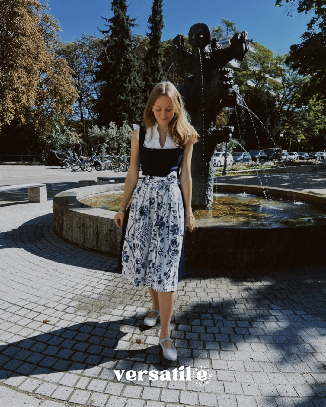 Munich dirndl rental: Alpenherz Marina with dark blue jacquard bodice and delicate embroidered tulle apron—ideal for Oktoberfest.