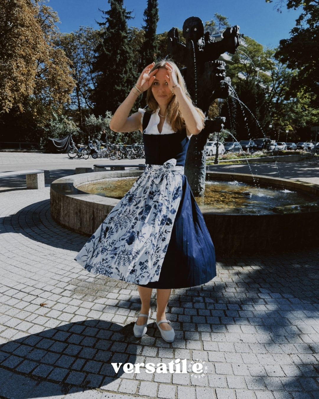 Munich dirndl rental: Alpenherz Marina with dark blue jacquard bodice and delicate embroidered tulle apron—ideal for Oktoberfest.