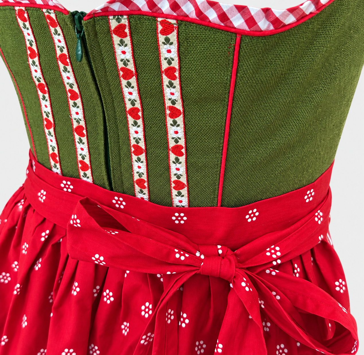Detail of green Apple of My Eye Dirndl bodice with heart ribbons, front zip and red apron bow