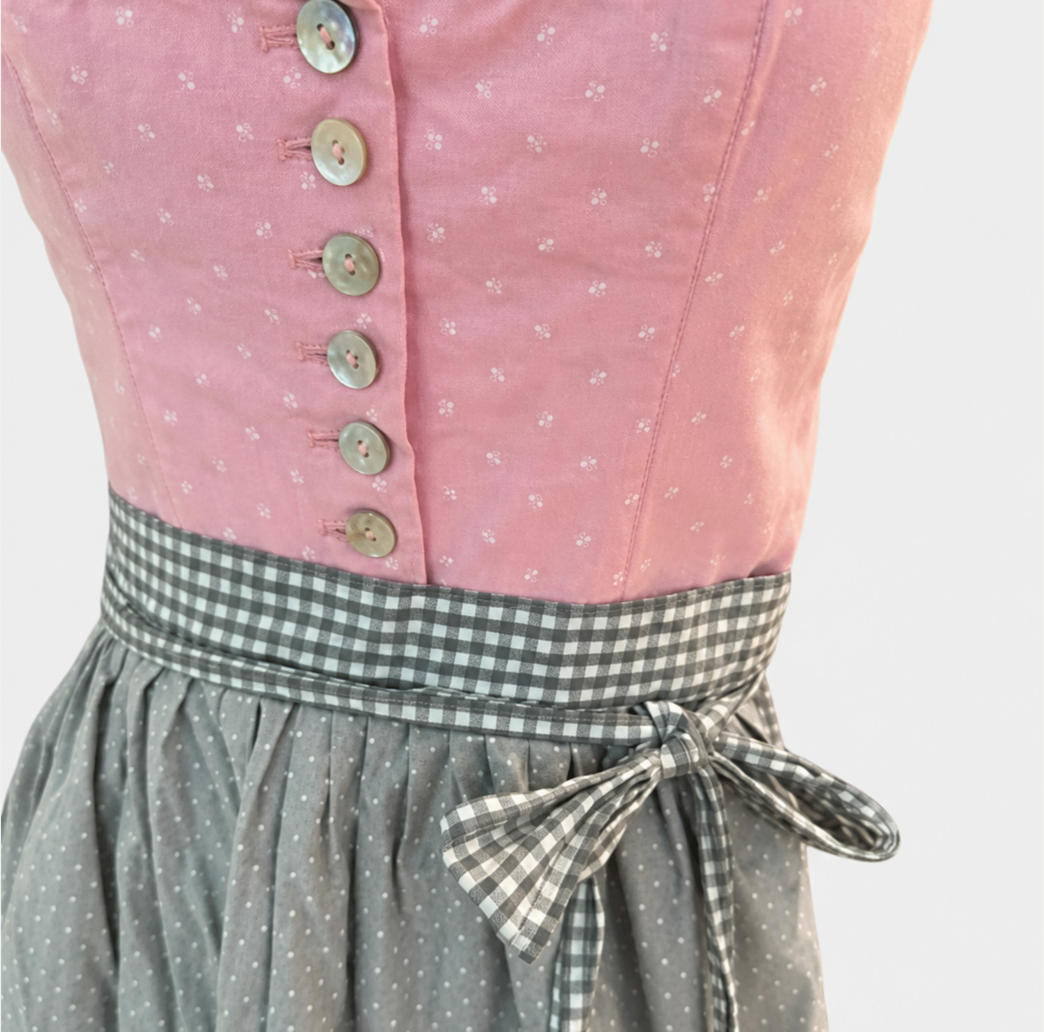 Detail of pink Berwin & Wolff Dirndl bodice with pale buttons, small white motifs and grey gingham apron bow