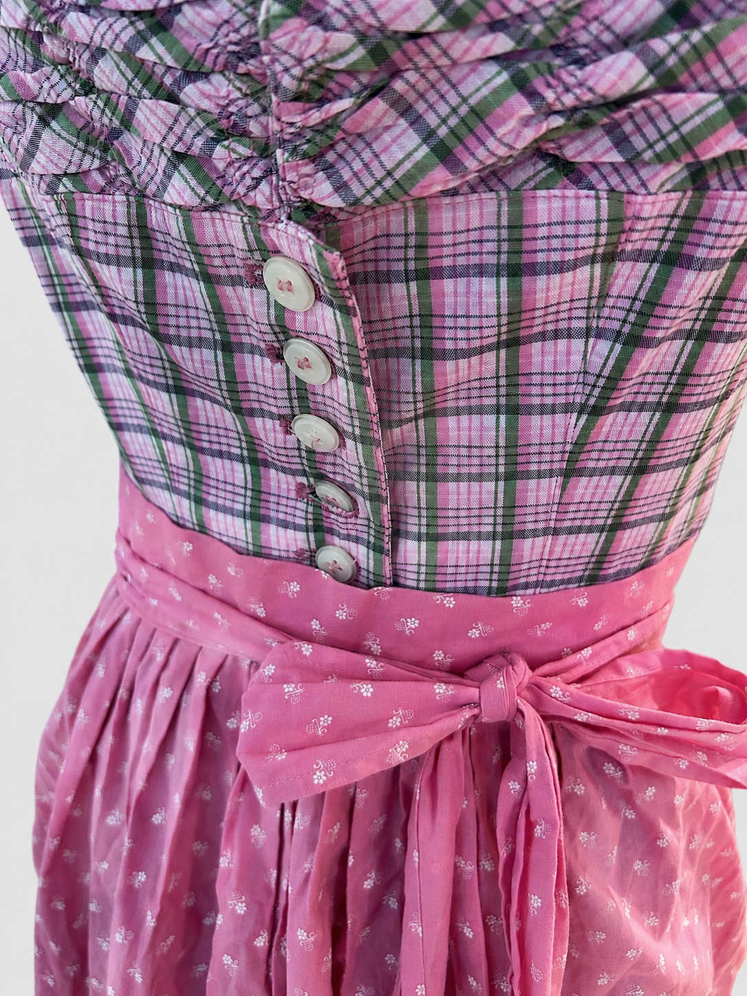 Close-up of Berwin & Wolff Dirndl with pink checked bodice, white buttons and bright pink apron bow